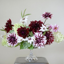 An elegant burgundy and white flower arrangement featuring hydrangeas, acidanthera, and dahlias Edge of Joy, Tartan and Rip City.