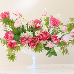 A lush fresh flower arrangement combining white daffodils and pink tulips in a white vase.